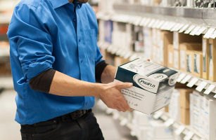 Man in blue shirt uniform pulling a ProFlo box off stocked shelves.