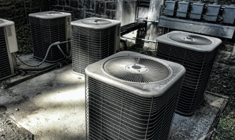 Three HVAC outdoor units on pavement.