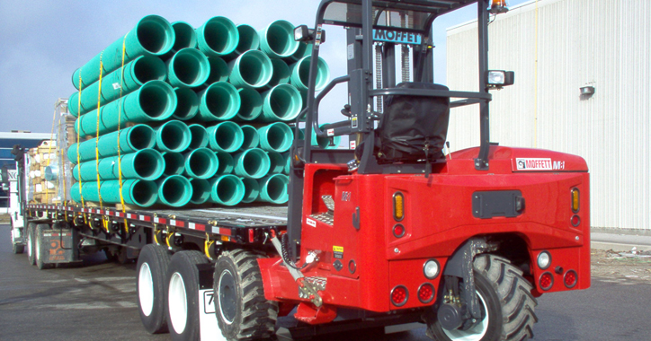 A flatbed truck carrying blue municipal water pipes.